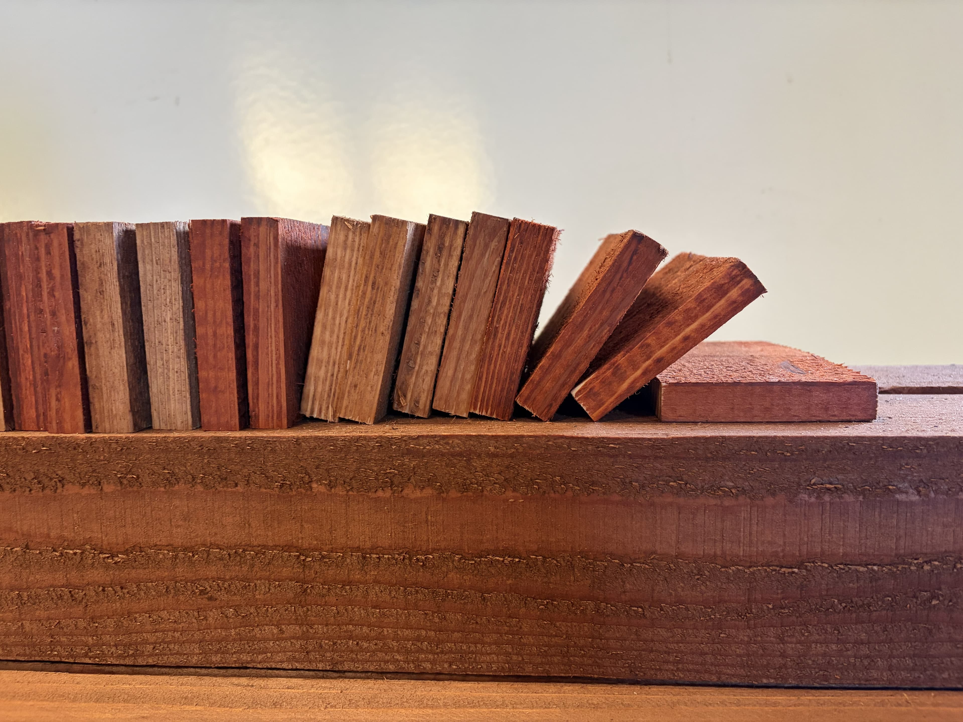 Small wood samples in various shades and grains lined up on a wooden beam.